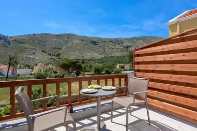 a patio with a table and chairs and mountains at Asymi Residences in Symi