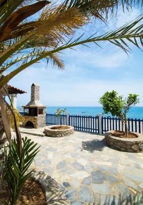 a stone patio with a stone fireplace next to the ocean at Casa d' Acqua in Archangelos