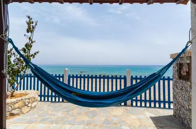 a blue hammock hanging on a fence near the ocean at Casa d' Acqua in Archangelos