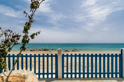a fence at the beach with the ocean in the background at Casa d' Acqua in Archangelos