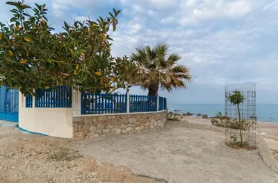 a blue fence and a palm tree next to the ocean at Casa d' Acqua in Archangelos