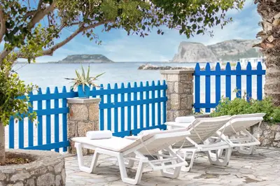 a group of white chairs and a blue fence at Casa d' Acqua in Archangelos
