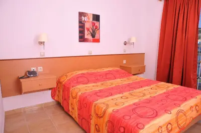 a bedroom with a bed with a red and yellow blanket at Argiro Village in Afantou
