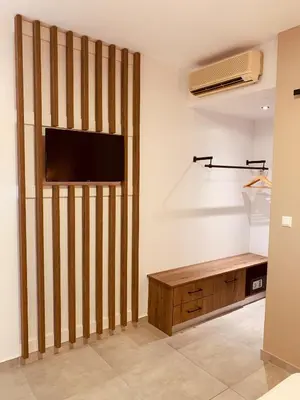 a living room with a wall with a tv and a wooden cabinet at Argiro Village in Afantou