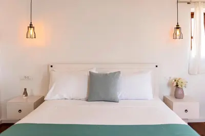a bedroom with a white bed with two night stands at Lindian Polis in Líndos