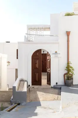 a white building with a wooden door in a courtyard at Lindian Polis in Líndos
