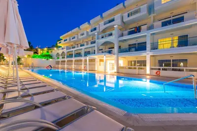 a swimming pool in front of a building at night at Lindos White Hotel & Suites in Líndos
