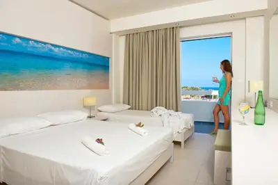 a woman standing in a hotel room with two beds at Lindos White Hotel & Suites in Líndos
