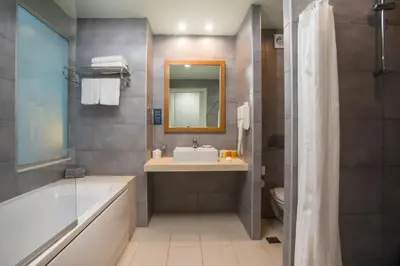 a bathroom with a tub and a sink and a mirror at Lindos White Hotel & Suites in Líndos