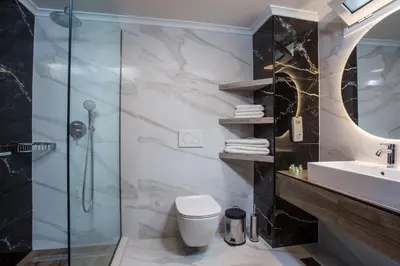 a bathroom with a shower and a toilet and a sink at Lindos White Hotel & Suites in Líndos