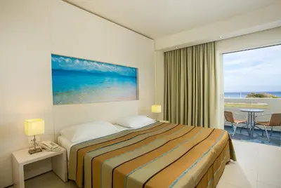 a hotel room with a bed and a view of the ocean at Lindos White Hotel & Suites in Líndos