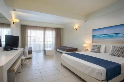 a hotel room with a bed and a flat screen tv at Lindos White Hotel & Suites in Líndos