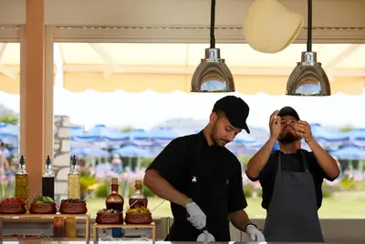two men standing in front of a table with bottles of wine at Lindos Princess Beach Hotel in Lardos