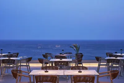 a restaurant with tables and chairs with the ocean in the background at Rodos Princess Beach Hotel in Kiotari