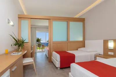 a hotel room with two beds and a desk at Rodos Princess Beach Hotel in Kiotari