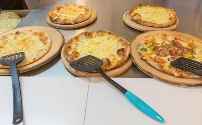 a group of pizzas sitting on a table with spatulas at Sun Palace Hotel in Faliraki