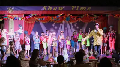 a group of people standing on a stage with a show time at Sun Palace Hotel in Faliraki
