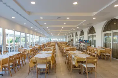 a dining room with tables and chairs and windows at Sun Palace Hotel in Faliraki