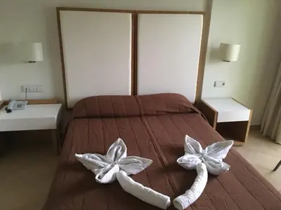 a bedroom with a bed with two flowers on it at Sun Palace Hotel in Faliraki