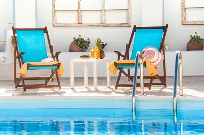 two chairs and a table next to a swimming pool at Villa Dionysus in Gennadi