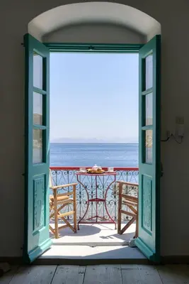 an open door to a patio with the ocean at Petridi House in Symi