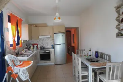 a kitchen with a refrigerator and a table with chairs at The Blue Leaf Family Villa in Gennadi