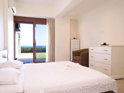 a white bedroom with a bed and a window at Luxury Villa Verna in Líndos