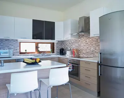 a kitchen with white appliances and white chairs at Luxury Villa Verna in Líndos