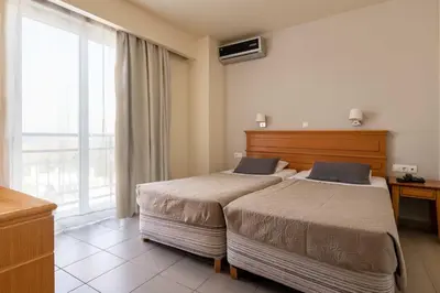a hotel room with two beds and a window at City Plus Rhodes Hotel in Rhodes Town