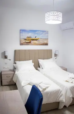 a bedroom with two beds and a blue chair at Aegean Horizon Beachfront Villas in Gennadi