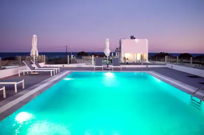 a swimming pool with blue water in front of a building at Aegean Horizon Beachfront Villas in Gennadi