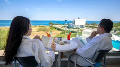 a man and woman sitting at a table near the beach at Aegean Horizon Beachfront Villas in Gennadi