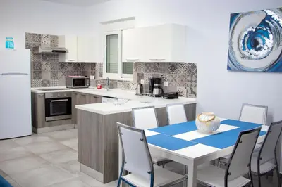a kitchen with a table and chairs and a refrigerator at Aegean Horizon Beachfront Villas in Gennadi