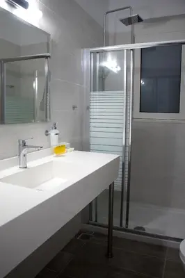 a white bathroom with two sinks and a shower at Aegean Horizon Beachfront Villas in Gennadi