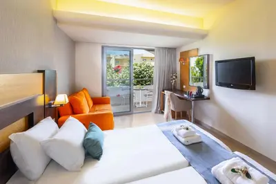 a bedroom with a bed and a couch and a television at Leonardo Kolymbia Resort Rhodes in Kolimbia