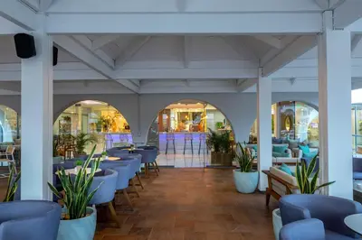 a restaurant with blue chairs and tables and windows at Leonardo Kolymbia Resort Rhodes in Kolimbia