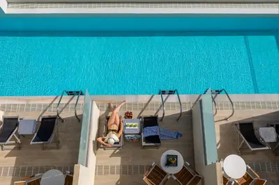 a woman is laying on the deck of a swimming pool at Leonardo Kolymbia Resort Rhodes in Kolimbia