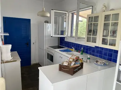 a kitchen with white cabinets and blue tiles at Afantou beach house in Kolimbia