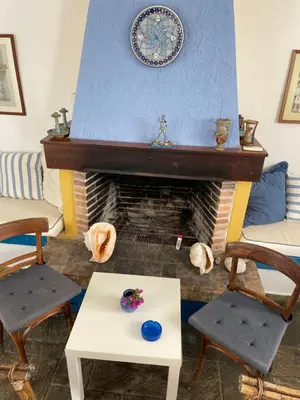 a living room with a fireplace with a table and chairs at Afantou beach house in Kolimbia