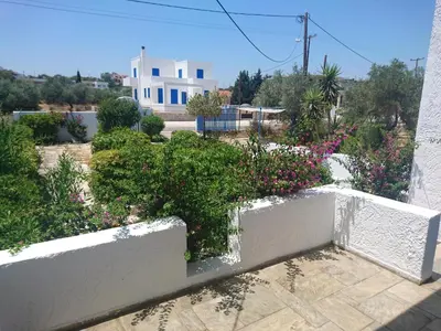 a white fence with bushes and flowers in front of a house at Afantou beach house in Kolimbia