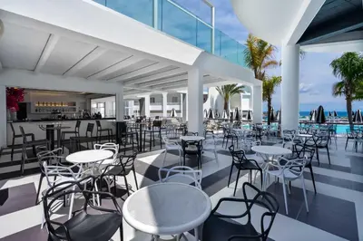 a restaurant with tables and chairs and the ocean at Venezia Resort Hotel & Spa in Faliraki