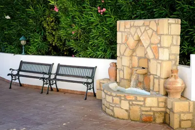 two benches sitting next to a stone fireplace at Pefkos Village Resort in Pefki Rhodes