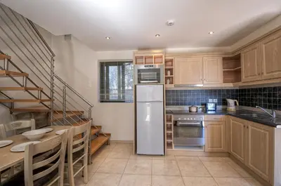 a kitchen with wooden cabinets and a spiral staircase at Pefkos Village Resort in Pefki Rhodes
