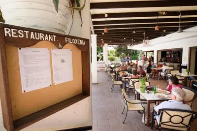 a group of people sitting at tables in a restaurant at Pefkos Village Resort in Pefki Rhodes