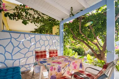 a table and chairs on the back porch of a house at Salora Studio-Apartments in Archangelos