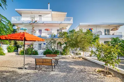 a patio with an orange umbrella and a table and chairs at Salora Studio-Apartments in Archangelos