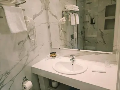 a white bathroom with a sink and a mirror at Ibiscus Hotel in Rhodes Town