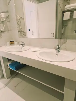 a white bathroom with two sinks and a mirror at Ibiscus Hotel in Rhodes Town