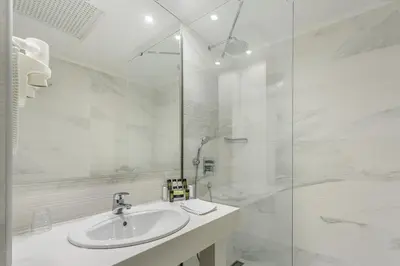 a white bathroom with a sink and a shower at Ibiscus Hotel in Rhodes Town