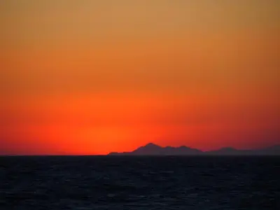 a sunset over the ocean with a mountain in the background at Nautilus Beach House in Paradeísion